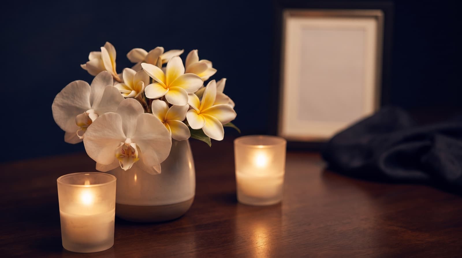 White orchids and plumeria beside candlelight